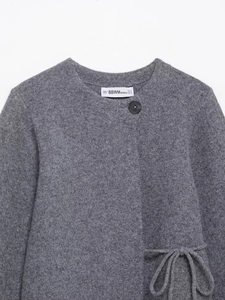 Gros plan d'un cardigan gris montrant l'étiquette et la texture du tricot