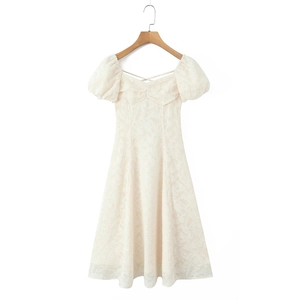 Détail de la dentelle florale sur la robe d'été beige à manches bouffantes et col carré