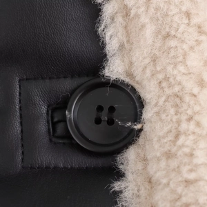 Detail of black faux leather texture with soft beige lamb wool collar and button