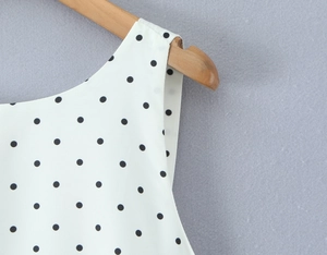 Close-up of crew neckline and black polka dot pattern on sleeveless summer top fabric
