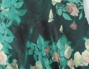 Détail du tissu en satin de soie avec imprimé rose réaliste sur un fond vert foncé