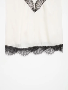 Detail eines weißen Seiden-Camisoles mit feiner schwarzer Wimpernspitze am V-Ausschnitt