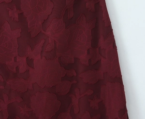 Detail of burgundy burnout fabric with three-dimensional rose floral textures