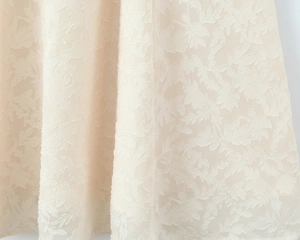 Détail macro de la broderie de feuilles sur le tissu de robe d'été crème