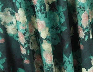 Vue détaillée du motif floral de roses vintage sur le tissu soyeux de la robe verte