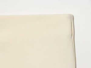 Detailed macro view of the beige woven fabric texture and neat edge stitching finish