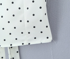 Detail of white fabric with black polka dots featuring neat stitching and hem process
