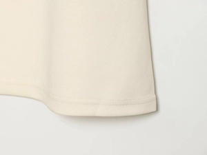 Detailed close-up of ivory knit skirt hem showing high-quality double-needle stitching