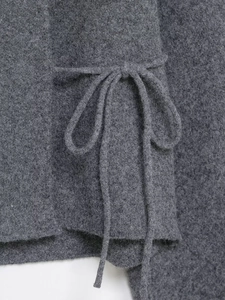 Détail d'un manteau en maille gris foncé avec une ceinture nouée élégante à la taille