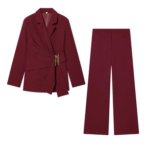 Détail de l'ensemble blazer bordeaux avec boucle dorée asymétrique et taille plissée élégante