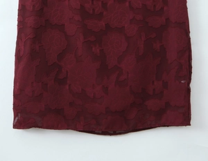 Detail of wine red dress featuring textured 3D rose floral jacquard pattern on fabric