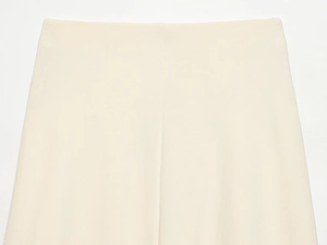 Close-up of the elegant twist knot detail and woven texture on this minimalist beige skirt