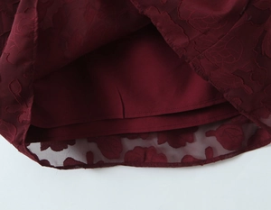 Detail of wine red dress hem featuring 3D floral burnout fabric and smooth satin lining