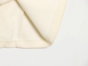 Detailed close-up of high-quality inner hem and seam stitching on beige midi skirt