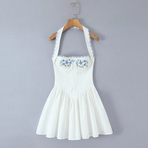 Detail of blue floral embroidery and wavy trim on white halter neck dress bodice