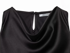 Detail of elegant black satin dress featuring a cowl neck and back button with teardrop cutout