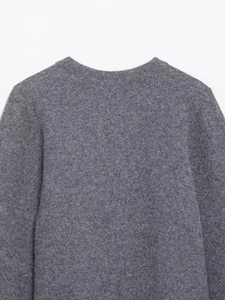 Vue détaillée du col du pull en tricot gris montrant la texture douce et le col rond
