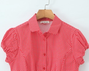 Detail view of red short sleeve blouse with white polka dots and classic collar
