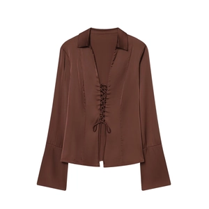 Detail of dark brown satin shirt featuring front lace-up closure and flared sleeves