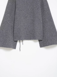 Gros plan du détail des poignets fendus sur un pull en tricot gris foncé doux