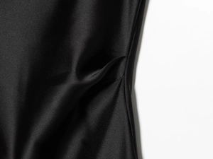 Macro detail showing the luxurious pleated texture and silk gloss of the black satin fabric