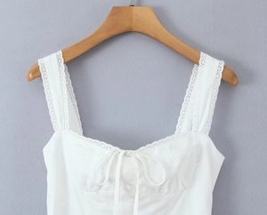Detailed view of white summer dress featuring delicate lace trim and ribbon bow tie