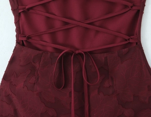 Close-up of wine red dress with backless lace-up design and floral embroidery detail