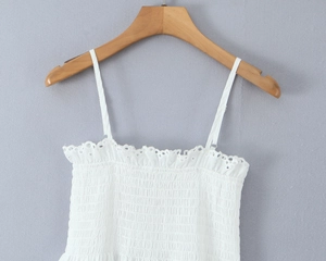 Detailed view of white eyelet lace embroidery and smocking on summer camisole top