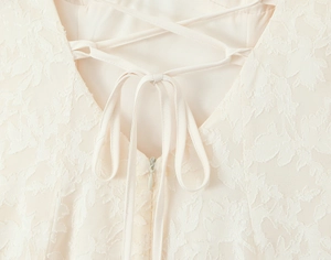 Détail du dos d'une robe en dentelle blanche avec laçage croisé et nœud élégant