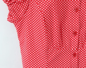 Close-up of red and white polka dot fabric with matching buttons on a slim shirt