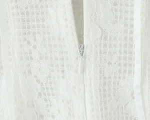 Détail de la fermeture éclair invisible et dentelle florale sur la robe blanche