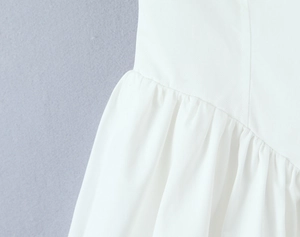 Detailed close-up of white dress fabric showing pleated seams and fine cotton texture