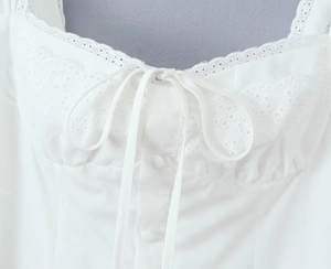 Close-up of heart neckline with eyelet embroidery, lace trim and elegant white bow detail