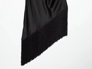 Detailed view of black satin dress hem featuring asymmetrical fringe and silk texture