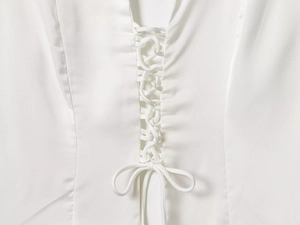 Detail of white satin shirt featuring adjustable drawstring ties and bow tie design