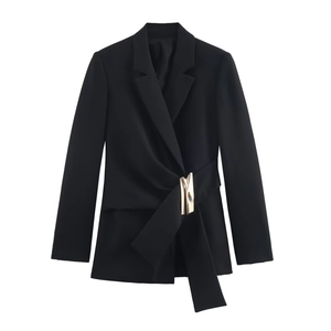 Détail d'un blazer noir avec une boucle dorée sculpturale sur une ceinture croisée