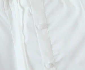 Detailed macro view of white woven fabric with matching fabric-covered buttons on the placket