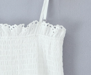 Detail of white top with adjustable straps, delicate eyelet lace, and smocking texture
