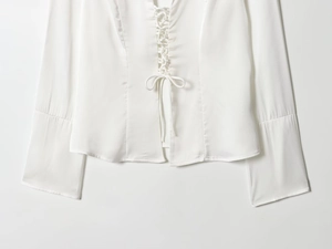 Detailed close-up of white satin shirt featuring front lace-up tie design and soft fabric texture