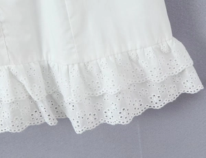Detail of white cotton dress hem featuring dual-layer ruffle and delicate eyelet embroidery