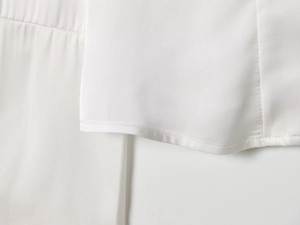 Detailed view of the smooth stitching and high-quality white satin fabric on shirt hem