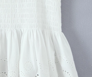 Detailed close-up of white smocking fabric and delicate eyelet embroidery textures