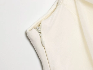 Detail of invisible zipper with teardrop pull on white slim fit mesh dress