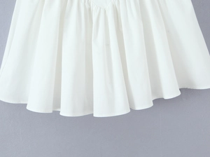 Detailed view of white pleated hemline featuring elegant ruffles and soft draped fabric