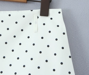 Detailed close-up of white polka dot fabric texture and waist band with hanger loops