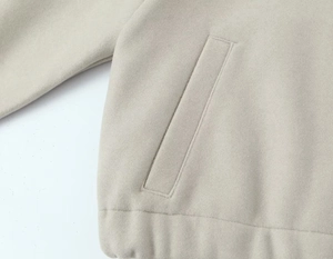 Détail de la poche passepoilée diagonale sur un tissu molletonné beige doux