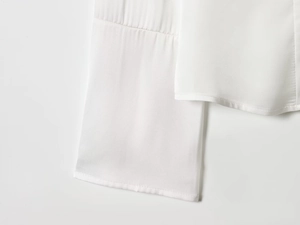 Macro shot of fine stitching and silky satin texture on white flared shirt cuff