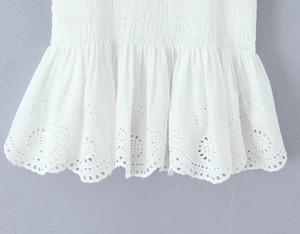 Detailed view of white cotton top with smocking texture and intricate lace embroidery