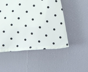 Close-up of black polka dot print on white fabric with high-quality hemmed edges