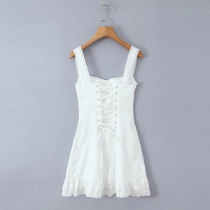 Detail of white mini dress featuring back corset lacing and delicate lace trim